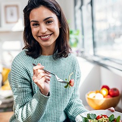 Woman smiling while eating healthy meal at home