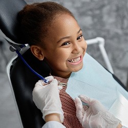 Child smiling while dental assistant puts on bib