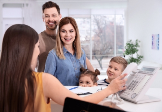 Familing discussing dental insurance benefits at reception desk