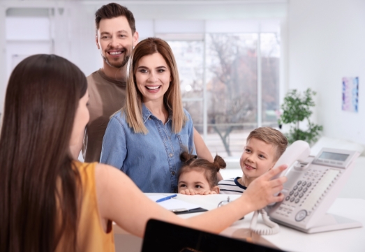 Familing discussing dental insurance benefits at reception desk