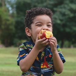 Child enjoying piece of fruit outside