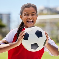 Child smiling while holding a soccer ball