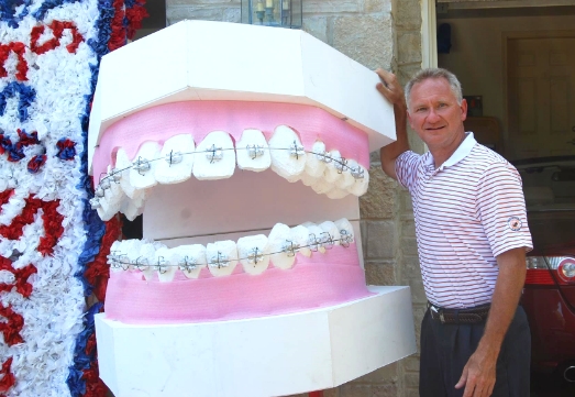 Doctor Kemp beside large model smile with braces