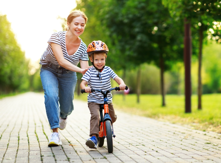 Mother helping child learn to ride a bike after emergency dentistry treatment