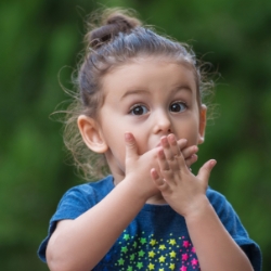 Young girl with cipped tooth covering her smile