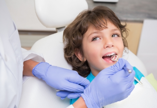 Dentist examining child after tooth colored filling restoration