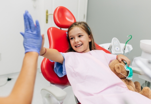 Child giving dentist a high five after pulpotomy