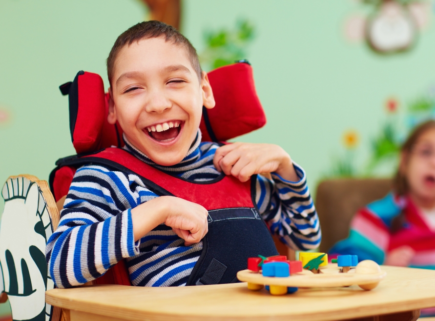 Child in wheelchair with healthy smile after special needs dentistry