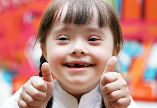 Young girl giving thumbs up after special needs dentistry