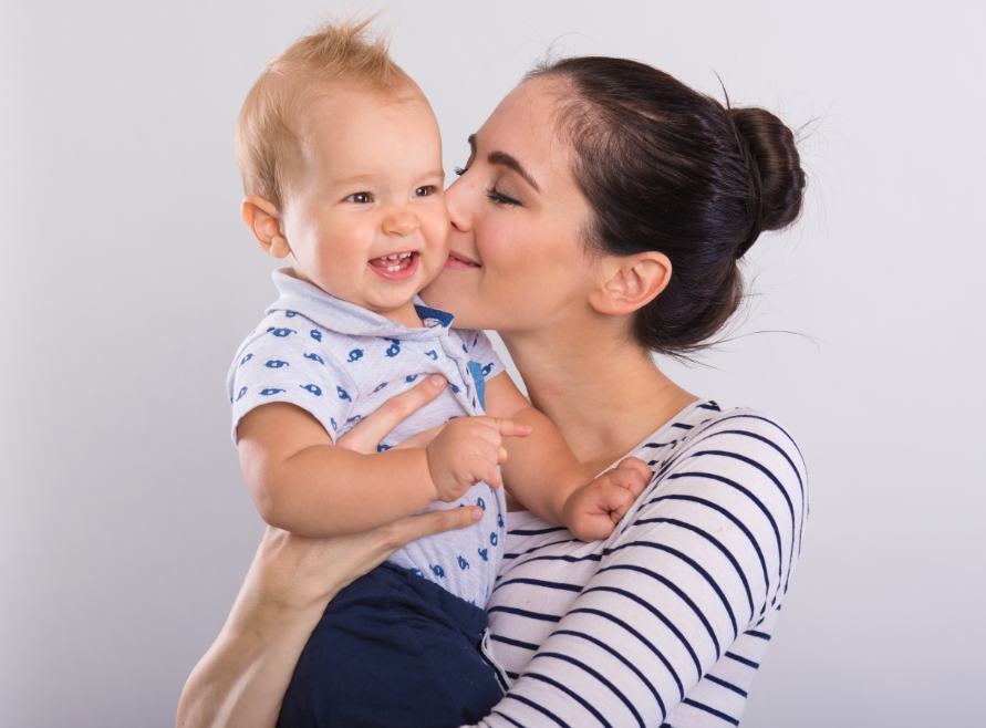 Mother kissing baby's cheek after lip and Tongue-Tie treatment