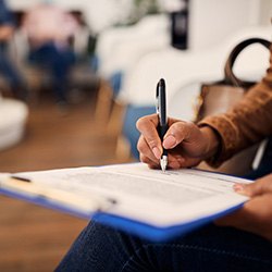 Woman filling out forms on blue clipboard