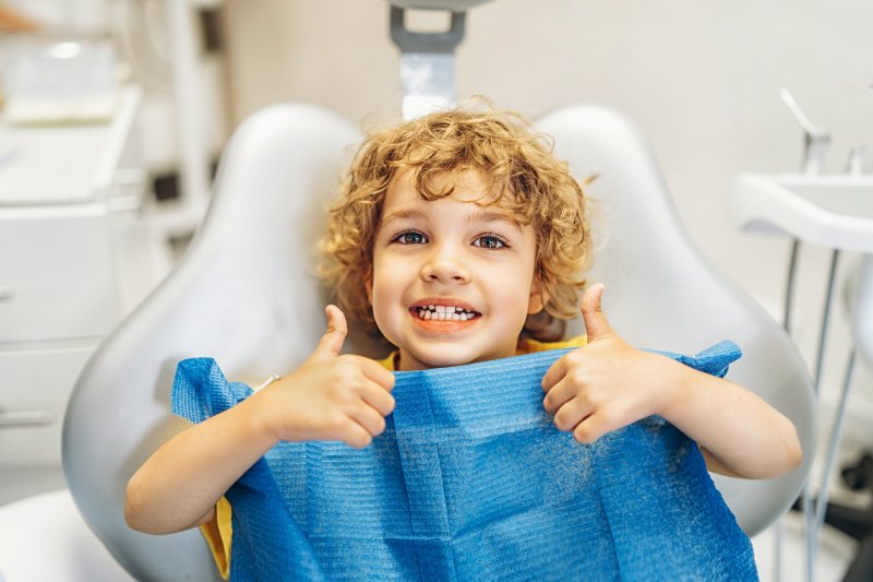 Young patient smiling and giving thumbs-up after getting dental fillings